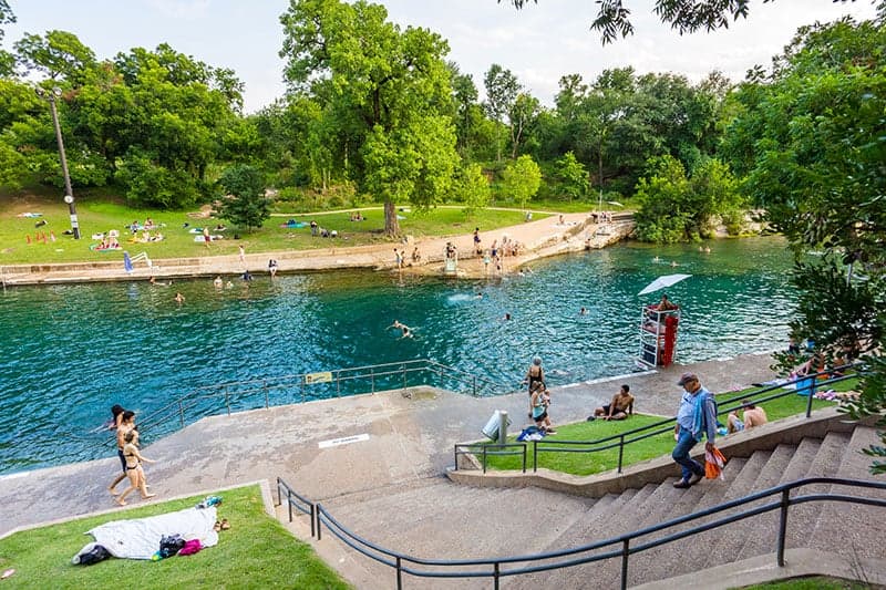 Natural swimming area with clear blue water surrounded by greenery